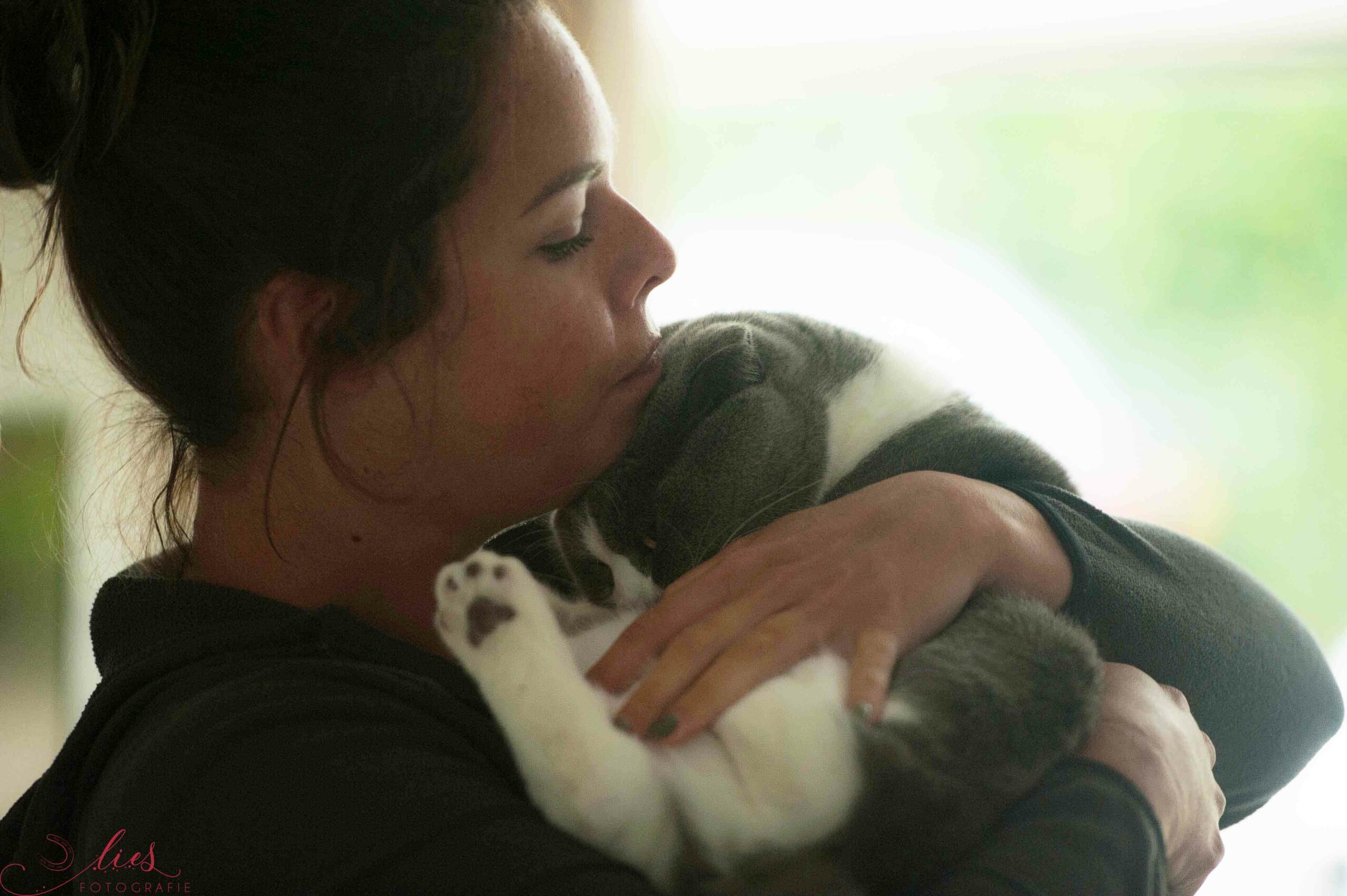 woman cuddling with grey and white cat
